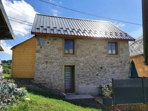 ein Steinhaus mit einem Metalldach in der Unterkunft L'Ophrys in Les Déserts