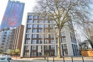 un edificio alto con un árbol delante de él en GRAND SERVICED APARTMENTS***** en Croydon