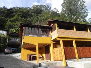 a yellow building with a table in front of it at Pousada Solar das Flores in Visconde De Maua