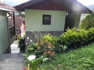 una casa con un jardín con flores delante en Pousada Solar das Flores en Visconde De Maua