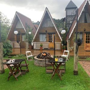 eine Terrasse mit Tischen und Stühlen vor einer Hütte in der Unterkunft Suítes no Chalé in Campos do Jordão