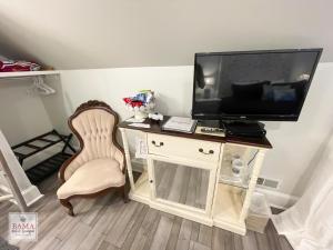 Habitación con escritorio, TV y silla. en Bama Bed and Breakfast - Wisteria Suite, en Tuscaloosa