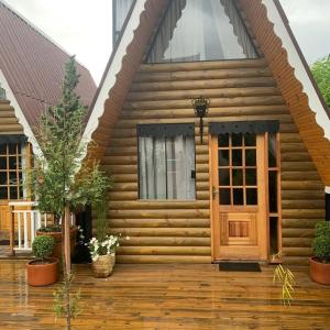 une maison en bois avec une porte en bois sur une terrasse dans l'établissement Suítes no Chalé, à Campos do Jordão