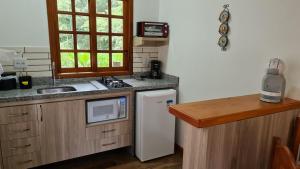a small kitchen with a sink and a refrigerator at Chalés Luar da Serra in Santo Antônio do Pinhal