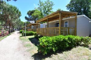 een kleine hut met een veranda en een houten terras bij Marina Family Village in Punta Marina