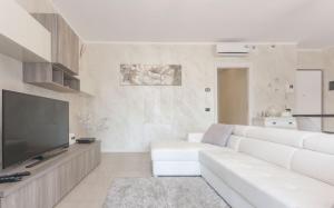 een woonkamer met een witte bank en een flatscreen-tv bij CaseOspitali - Casa LA VELA raffinato bilocale con balcone in Cernusco sul Naviglio