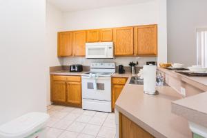 uma cozinha com armários de madeira e um forno de fogão branco em Cozy Three Bedrooms Townhome at Lake Berkley Resort (1123) em Kissimmee