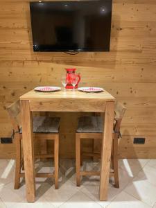 a wooden table with four chairs and a television on a wall at L'aiguille de L'M in Chamonix-Mont-Blanc