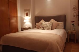 um quarto com uma cama grande com lençóis brancos e almofadas em La Casa de Sillería em Toledo