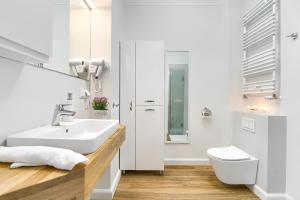 uma casa de banho branca com um lavatório e um WC em Apartament Maya em Szczecin
