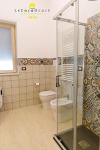 uma casa de banho com um WC e uma cabina de duche em vidro. em Le Coco Beach Apartaments em Ascea