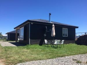 a black house with a table and an umbrella at Cabañas Tinajas hidromasaje Chanlelfu in Puyehue