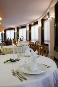 jadalnia ze stołami z białymi talerzami i sztućcami w obiekcie Hotel sirena w Cesenatico