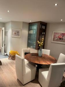 a dining room with a wooden table and white chairs at ERNA in Blankenberge +24 photos