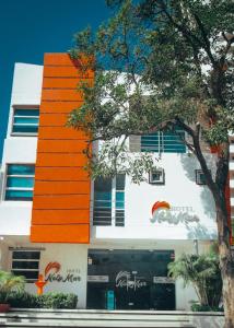 un bâtiment orange et blanc avec un arbre devant lui dans l'établissement Hotel NelyMar, à Santa Marta