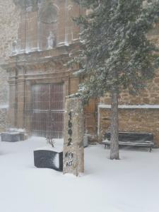 un edificio con un árbol y un banco en la nieve en Apartamento María en Valdelinares VUTE-21-041, en Valdelinares