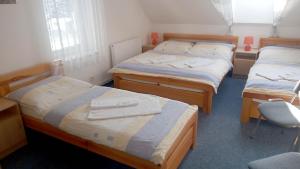 Habitación con 3 camas y silla en Penzion Pristav, en Lipno nad Vltavou