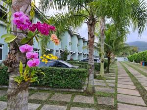 een straat tegenover een hotel met palmbomen en bloemen bij Casinha de Boneca em Juquey in Juquei