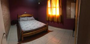 Dormitorio pequeño con cama en habitación púrpura en Cabañas Don Victor en San Rafael
