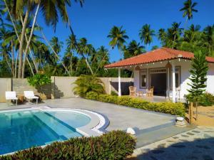 a villa with a swimming pool and a house at Sleeping Elephant Beach Resort in Tangalle