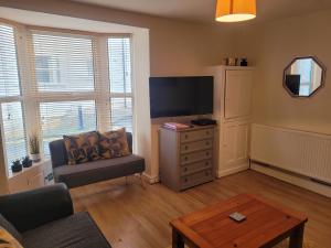 a living room with a tv and a chair and a table at Large 5 bed town-centre home close to the beach, sleeps 9 in Aberystwyth