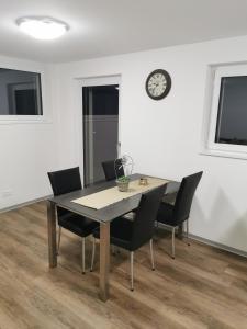 a dining room table with chairs and a clock on the wall at Studio Rämschfädra in Sankt Niklaus