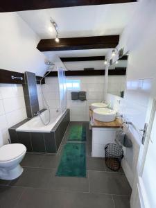 ein Badezimmer mit zwei Waschbecken, einer Badewanne und einem WC in der Unterkunft Pauernhof Ferienwohnungen in Bad Nenndorf