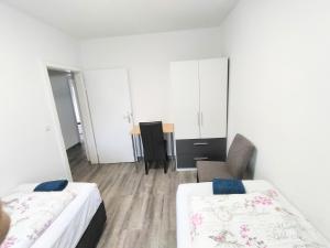 um quarto branco com 2 camas e uma cadeira em FMI 44Accommodation em Rüsselsheim