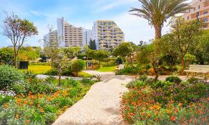 a park with a pathway and flowers and buildings at Apartamento T2 Club Amarílis - Portimão in Portimão