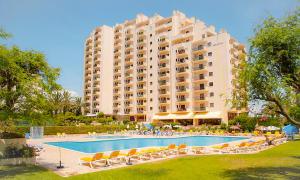 a large hotel with a pool and chairs and a building at Apartamento T2 Club Amarílis - Portimão in Portimão