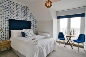 a bedroom with a large bed and two blue chairs at Beaches Guest House in Southend-on-Sea