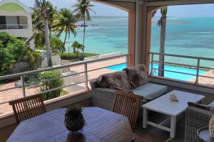 a porch with a table and chairs and the ocean at ilococo in Sainte-Anne