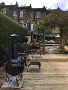 a patio with chairs and a fireplace on a wooden deck at The Yorkshire Hosts - Fall in Green Cottage in Haworth