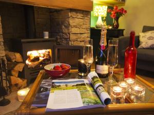 a table with a book and wine glasses and a fireplace at The Yorkshire Hosts - Fall in Green Cottage in Haworth