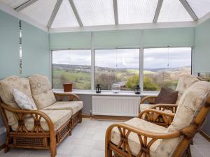 a conservatory with rocking chairs and a large window at The Yorkshire Hosts - Fall in Green Cottage in Haworth