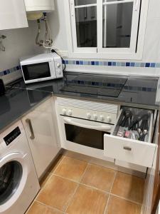 a kitchen with a microwave and a washer and dryer at Precioso apartamento en complejo residencial. in Alcaucín