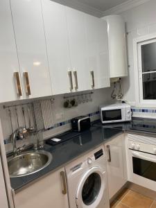 uma cozinha com um lavatório e uma máquina de lavar roupa em Precioso apartamento en complejo residencial. em Alcaucín