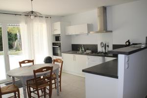 cocina con armarios blancos, mesa y sillas en Bel appartement en campagne en Grane