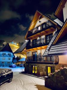 ein Gebäude mit Balkonen und einem Auto im Schnee in der Unterkunft Willa Dolina Harenda in Zakopane
