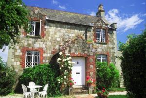 Casa de ladrillo con puerta blanca, mesa y sillas en Harry's at Spire Cottage Dog friendly cottage, en Chichester
