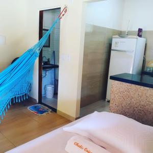 a hammock in a room with a kitchen and a refrigerator at Chalés Caiçara Praia de Ponta Grossa in Icapuí