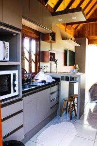 a kitchen with a sink and a microwave at Chalés Rota das Cachoeiras in Urupema