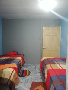 1 dormitorio con 2 camas y puerta blanca en Hospedaje Arvakeni en San Cristóbal