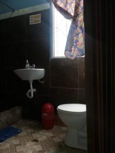 baño con aseo y lavabo y ventana en Hospedaje Arvakeni, en San Cristobal