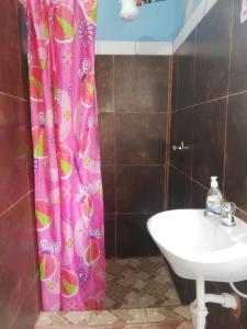 a bathroom with a pink shower curtain and a sink at Hospedaje Arvakeni in San Cristobal