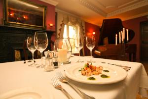una mesa con un plato de comida y copas de vino en Kilcooly's Country House Hotel en Ballybunion