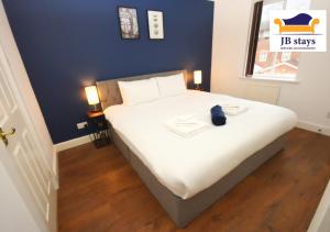 1 dormitorio con 1 cama blanca grande y pared azul en 4 Bed Townhouse/Free Parking, en Mitcham