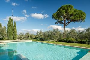 una piscina con un árbol en el fondo en Fattoria La Loggia en San Casciano in Val di Pesa