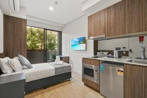 a kitchen with a bed and a sink in a room at Coogee Studio Apartments in Sydney