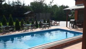 a pool with chairs and tables and a gazebo at Apartmány Sophia 7 in Velké Losiny